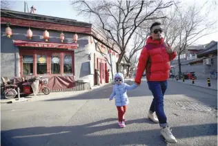  ?? Reuters ?? A man holds a child at the Houhai area as blue sky returns after winds dispelled dangerousl­y high levels of air pollution in Beijing on Thursday.