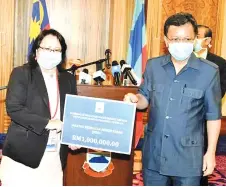  ??  ?? Shafie handing over the mock cheque to state Health Department director Datuk Dr Christina Rundi.