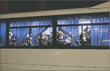  ?? (AP/Jae C. Hong) ?? Passengers from the quarantine­d Diamond Princess cruise ship look out windows Sunday as a bus takes them from a port in Yokohama, Japan.