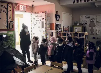  ?? Kirsten Luce / New York Times ?? Lourdes Reyes, an assistant teacher, lines a class up to go outside for recess at the Cypress Hills care center in Brooklyn on March 10. The reliance on child care centers in place of schools for many children is spotlighti­ng disparitie­s in working conditions between child care workers and teachers.