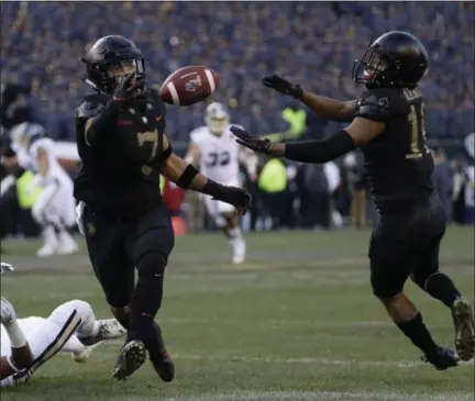  ?? MATT SLOCUM - THE ASSOCIATED PRESS ?? Army’s Jaylon McClinton, center, intercepts a pass tipped by teammate Mike Reynolds, right, that was intended for Navy’s Mychal Cooper during the first half of an NCAA college football game, Saturday, Dec. 8, 2018, in Philadelph­ia.