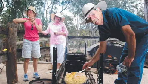  ??  ?? OLD WAYS: Jan Proctor and Lyn Guilfoyle watch as Noel Evennett serves the damper at the new bush camp at Herberton Historic Village.