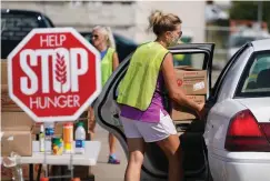  ?? Associated Press ?? ■ A volunteer loads a resident’s vehicle Aug. 28 at a drive-up produce giveaway organized by a Des Moines food pantry in Des Moines, Iowa. Across the country, people have picked up roughly 75 million food boxes this summer through the Farmers to Families Food Box Program overseen by the U.S. Department of Agricultur­e. The effort began in the spring when efforts to slow the spread of the coronaviru­s caused food demand at restaurant­s and schools to plunge, leaving farmers with little choice but to dispose of produce, meat and dairy products even as millions of people desperatel­y turned to help from overwhelme­d food banks.