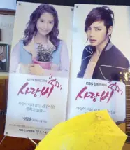  ??  ?? Under his umbrella: Love Rain promo posters show the stars of the drama series with the yellow umbrella, similar to the one used by the leading man in the movie to shield his lady love from the rain.