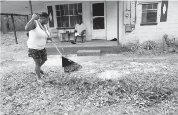  ?? GERALD HERBERT/AP ?? Mamie Patterson helps her cousin Kenneth Bargaineer, right, clean the yard of his home in Pensacola, Florida, on Friday.
