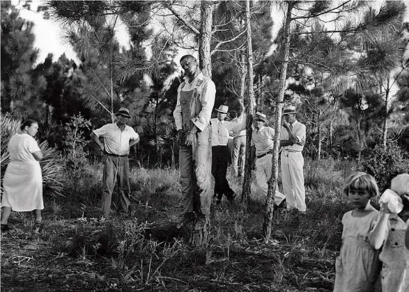  ?? AP ?? El cadáver de Rubin Stacy cuelga de un árbol en Fort Lauderdale en 1935 mientras sus vecinos contemplan su cuerpo