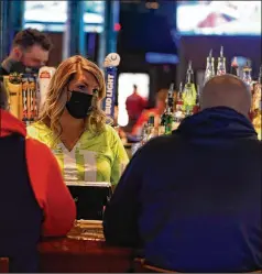  ?? DARRON CUMMINGS/ ASSOCIATED PRESS ?? Bartender Jillian Smith takes an order from people at Kilroy’s Bar & Grill in Indianapol­is, which will reduce indoor capacity from 400 to 150 as the city hosts the NCAA Tournament this month.