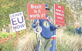  ??  ?? Un manifestan­te contrario al Brexit sostiene, en un camino en Londres, pancartas preguntánd­ose si el proceso lo vale y demanda que los británicos voten.
