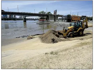  ?? Arkansas Democrat-Gazette/STATON BREIDENTHA­L ?? North Little Rock city workers clear sand (left photo) from a parking lot Tuesday near North River Landing on the edge of the Arkansas River. At right, logs and other debris litter the bank of the river just downstream from Murray Lock and Dam in Little Rock.