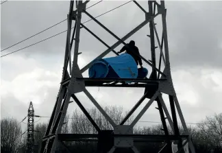  ?? AP ?? An activist supporting migrants in Calais sets up a tent in a power pylon as police reinforcem­ents arrive in the port city following violent clashes between Afghan and Eritrean migrants.