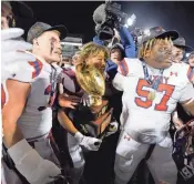  ?? ?? Bixby's Kordell Gouldsby carries the trophy after winning the Class 6A-I football state title on Dec. 1 in Edmond. Bixby beat Jenks 49-21.