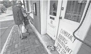  ?? AP ?? Passersby examine the menu at the Red Hen Restaurant on Saturday.