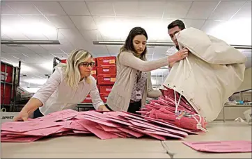  ?? RICH PEDRONCELL­I / AP FILE ?? Election workers Heidi McGettigan, left, Margaret Wohlford, center, and David Jensen unload a bag of ballots brought in a from a polling precinct to the Sacramento County Registrar of Voters office in Sacramento in this 2018 file photo. Mail-in ballots begin going to voters by mid-May for the primary election on June 7.