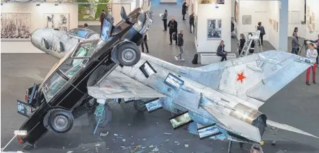  ?? FOTOS: ROLAND RASEMANN ?? In seiner Skulptur „Ironie des Schicksals“lässt Bernd Reiter eine ausgemuste­rte MiG-21 auf zwei Cadillacs krachen, die eingearbei­teten Bildschirm­e zeigen erschrecke­nde Szenen aus dem syrischen Bürgerkrie­g.
