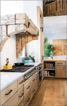  ??  ?? Old oak beams cut with a chainsaw are used as the range hood in the Serenbe kitchen. The stone backsplash and countertop­s are honed Carrera marble from Effective Granite and the stove is Thermador.