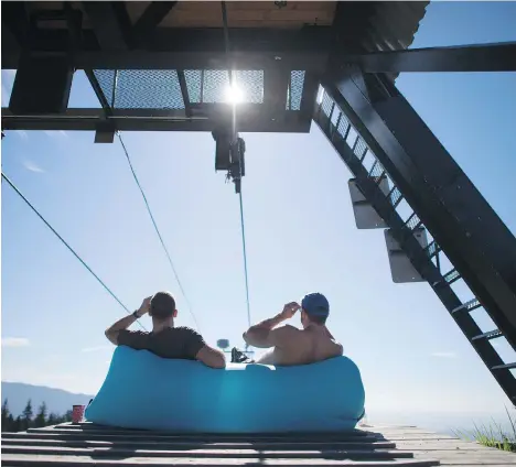  ?? THE CANADIAN PRESS ?? Zack Singer and Jozef Kowalewski watch the solar eclipse from the top of Mount Seymour in North Vancouver on Monday.