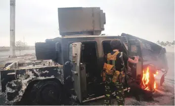  ?? AFP ?? An Al Houthi militant inspects a burning armoured vehicle hit in an air strike during clashes between fighters loyal to exiled President Abd Rabbo Mansour Hadi and Al Houthis in Hodeida.