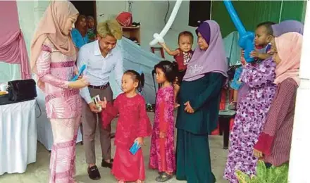  ?? [FOTO SITI ROHANA IDRIS /BH] ?? Nik Muhammad Ryzal bersama You Narae memberi duit raya kepada kanak-kanak di Kampung Petani Sering, Kota Bharu, ketika sambutan Aidilfitri baru-baru ini.