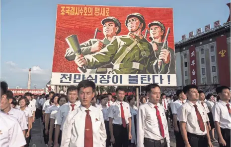  ?? PHOTOS BY KIM WON JIN, AFP/GETTY IMAGES ?? A propaganda poster looms over a rally in support of North Korea’s stance against the United States at Kim Il Sung Square.