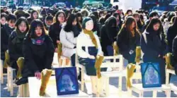  ??  ?? People sit around a comfort woman statue, during an event commemorat­ing the deaths of eight former sex slaves this year, in Seoul on Wednesday.