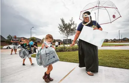  ??  ?? Assistant principal Miranda Cummings greets twins Brynley and Brantley Trautwein, 5, at McElwain Elementary School.