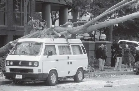  ??  ?? A tree that toppled in the storm rests on a van in the west end of downtown Vancouver on Saturday.