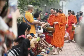  ??  ?? Give and take: The giving of alms is popular with tourists in Luang Prabang but there are other ways to have a rewarding experience in another country. — The Vientiane Times/Asia News Network