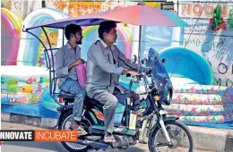  ?? — DC ?? Bike riders protect themselves with a specially-designed umbrella at Saidabad.