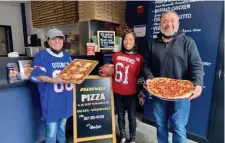  ?? CourTESY of KErrY bYrNE ?? SLICE OF A RIVALRY: Boardwalk Pizza employee Lisa Palingo (left), manager Rachel Estepa (middle) and owner Donato Frattoroli are seen with pizzas as their restaurant will help continue the Quincy-North Quincy rivalry even without the traditiona­l Thanksgivi­ng Day game this year.