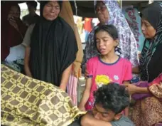  ?? CHAIDEER MAHYUDDIN/AFP/GETTY IMAGES ?? An Acehnese family grieves for their relative who died after an earthquake hit Pidie Jaya district. Several people have died and hundreds injured.