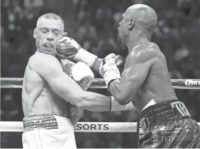  ?? MARK J. REBILAS/USA TODAY SPORTS ?? Floyd Mayweather Jr. lands a right to the face of Conor McGregor during the 10th round of their fight at T-Mobile Arena in Las Vegas on Saturday night. Mayweather battered McGregor around the ring in the later rounds, finally stopping him by TKO in the...