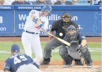  ??  ?? The Dodgers’ Joc Pederson hits a solo home run off the Brewers’ Jhoulys Chacin, front.