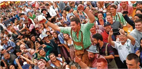  ?? FOTO: AP PHOTO/MATTHIAS SCHRADER ?? In L ederhose und mit Bier in der Hand f eierten erste Besucher am Samstag die Eröf f nung des 185. Oktob erf estes in M ünchen.