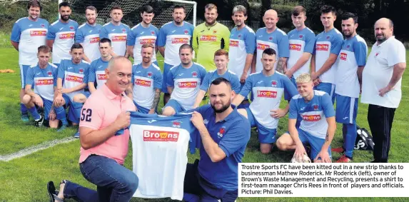  ?? Picture: Phil Davies. ?? Trostre Sports FC have been kitted out in a new strip thanks to businessma­n Mathew Roderick. Mr Roderick (left), owner of Brown’s Waste Management and Recycling, presents a shirt to first-team manager Chris Rees in front of players and officials.