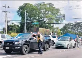  ?? Frederic J. Brown AFP/Getty Images ?? POLICE OFFICERS and the National Guard check the identifica­tion of drivers before allowing evacuees to return home at the Leilani Estates in Pahoa, Hawaii.