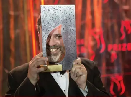  ?? CHRIS YOUNG/ THE CANADIAN PRESS ?? Michael Redhill holds up his award Monday night at the Ritz-Carlton in Toronto after winning the $100,000 Giller Prize.