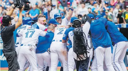  ??  ?? Jays players celebrate after Steve Pearce hit a walk-off grand slam to defeat the Athletics in the 10th inning.