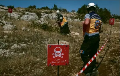  ?? NICOLE TUNG/NEW YORK TIMES ?? Volunteers with the White Helmets prepared to sweep farmland in Termanin, Syria, for bombs.