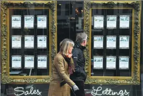 ?? REUTERS ?? A couple walk past a window display of an estate agent in London on Feb 7, 2017.