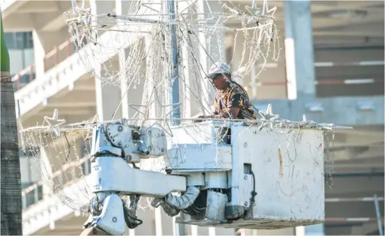 ?? PHOTOGRAPH­S BY KING RODRIGUEZ FOR THE DAILY TRIBUNE ?? A WORKER makes use of the boom truck as he removes the Christmas decor along Jose W. Diokno Boulevard in Pasay on Wednesday, 24 January.