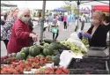  ??  ?? Julie Smith of Lodi points to the produce she wants as she is being helped by Xiong Produce’s Lorthao Xiong.