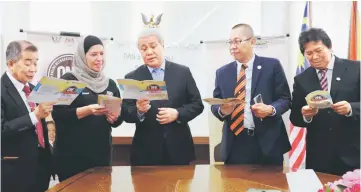  ??  ?? (From left) Naroden, Zahrah, Awang Tengah, Abdullah and Mussen look at the carnival booklet.