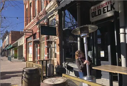  ?? MEAD GRUVER — THE ASSOCIATED PRESS ?? Whiskey tasting room manager Melinda Maddox moves a propane-fueled outdoor space heater in downtown Fort Collins, Colo., in preparatio­n for opening on Jan. 6.