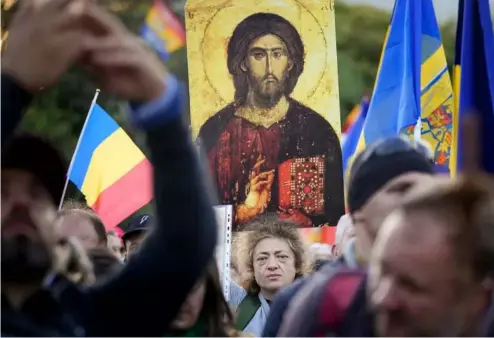  ?? ?? A woman holds an icon during an anti-government and anti-vaccinatio­n protest organised by the far-right AUR party in Bucharest, October 2021 AP Photo/Vadim Ghirda