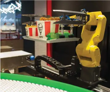  ?? BLOOMBERG ?? A robotic arm serves food from a conveyor belt in a KFC restaurant in Moscow. Demand for industrial robots has accelerate­d in recent years