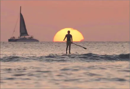  ?? The Associated Press ?? A paddleboar­der enjoys the water at sunset off Waikiki Beach in Honolulu. If that person came from Canada, he’d better have travel insurance in case something goes wrong.