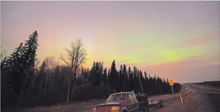  ?? JONATHAN HAYWARD THE CANADIAN PRESS ?? The northern lights shine above the glow from a wildfire in northern Alberta, which is part of Canada’s boreal forest.