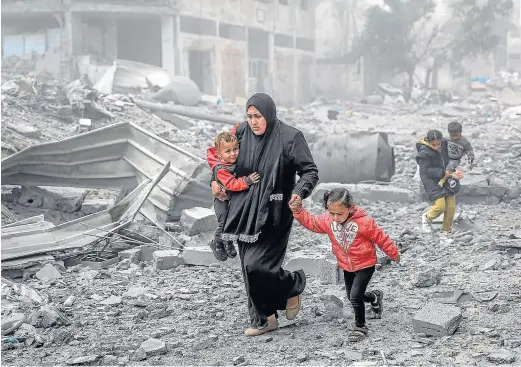  ?? AFP ?? Una mujer huye con sus hijos del barrio donde se asienta el hospital Al-Shifa durante el asalto del Ejército israelí.