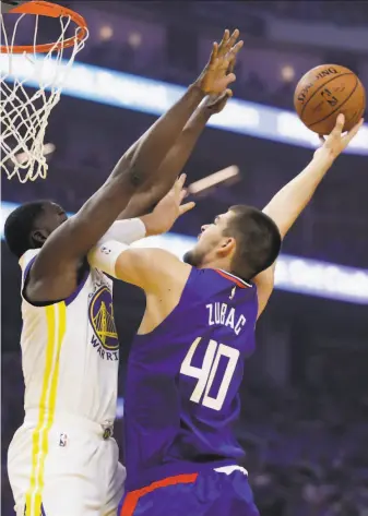  ?? Ben Margot / Associated Press ?? The Clippers’ Ivica Zubac shoots against the Warriors’ Draymond Green, who missed some time in the first half with an injury but returned and finished with 11 points in 28 minutes.