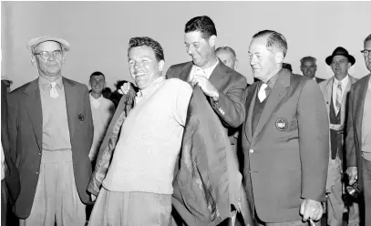  ?? AP FILE PHOTOS ?? Jack Burke Jr. is helped by Cary Middlecoff as he puts on the traditiona­l green jacket after winning the Masters at Augusta National Golf Course in Augusta, Georgia, on April 8, 1956.